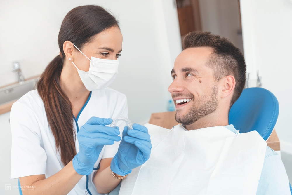 Orthodontist showing Invisalign clear aligners to a smiling patient, highlighting alternatives to braces in Tulsa, OK