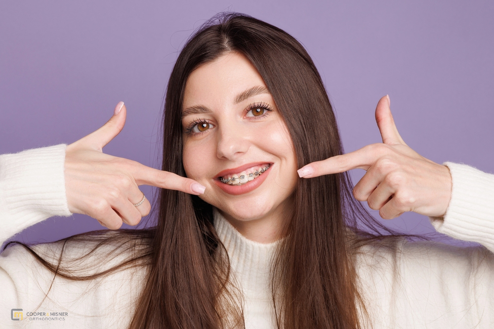 happy girl pointing at her metal braces after understanding how long do braces take in Tulsa, OK