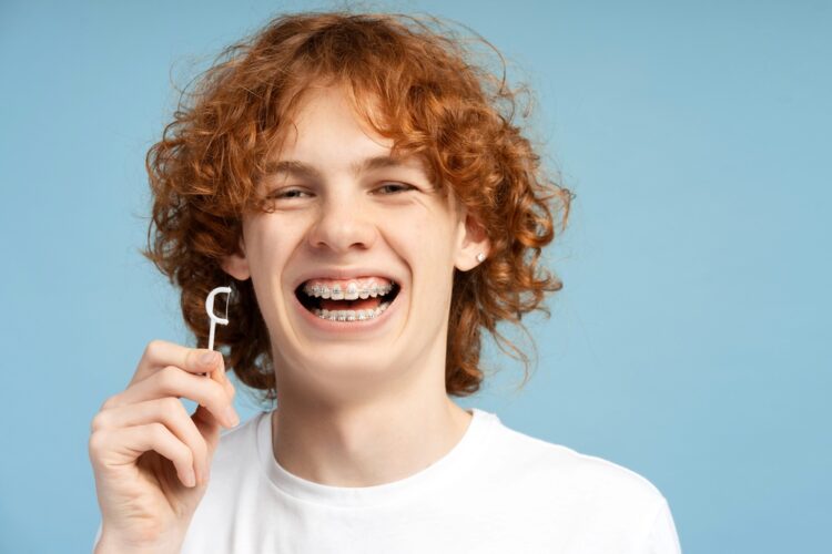 close up image smiling teenager curly red hair metal braces - How to Floss with Braces in Tulsa, OK