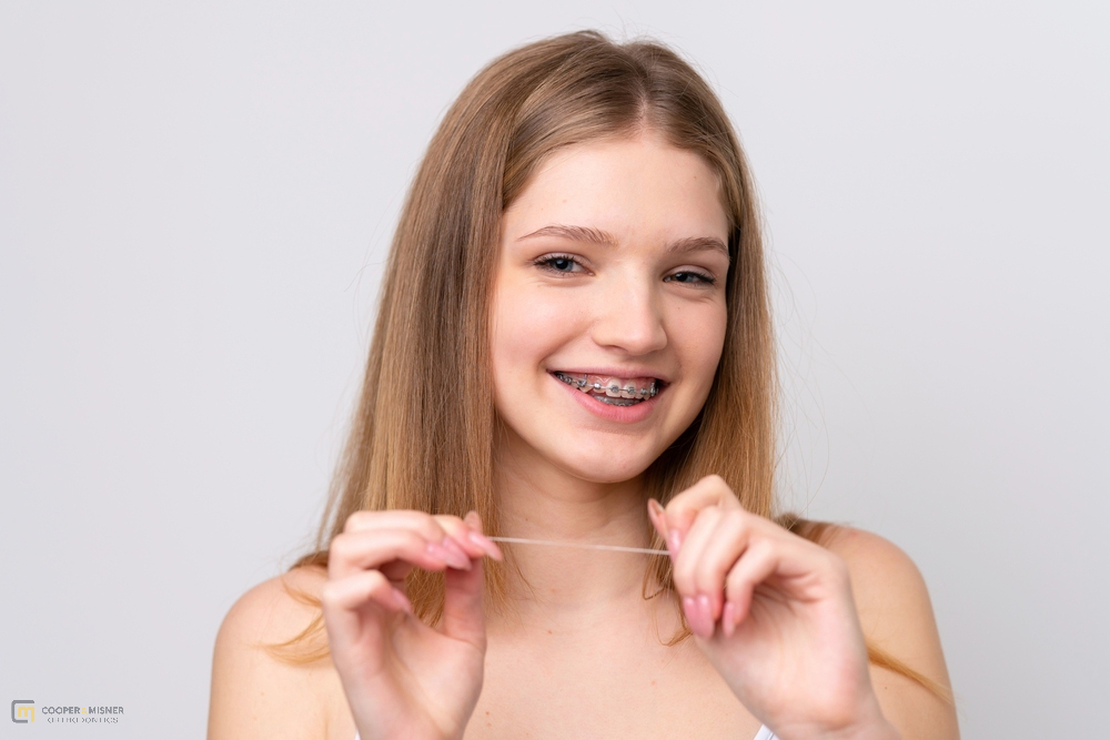 teenager russian girl with metal braces and floss isolated white background - How to Floss with Braces in Tulsa, OK