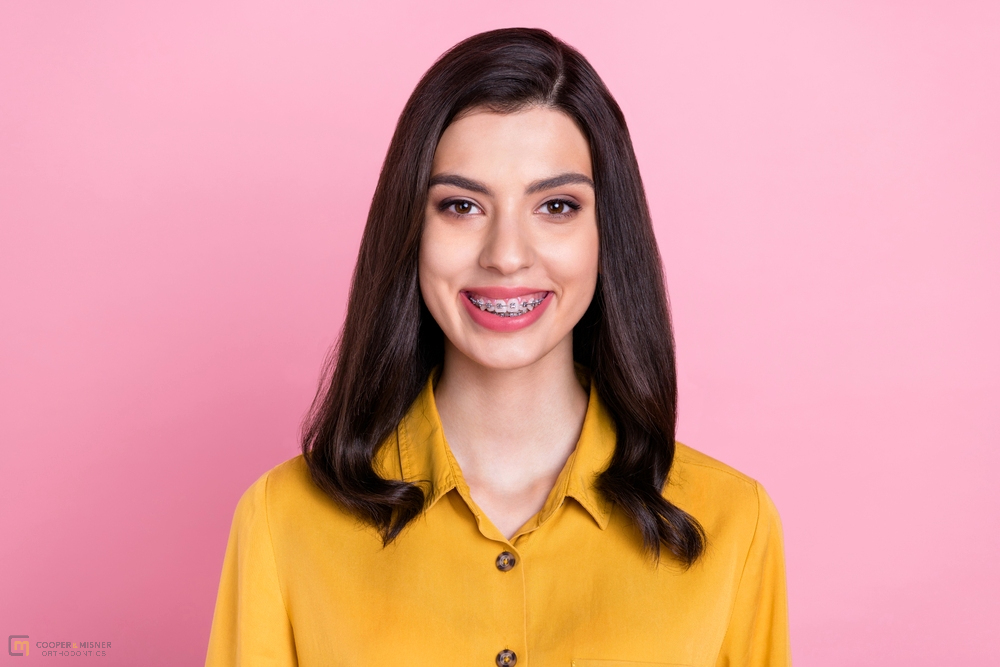 photo of nice optimistic brunette hair young lady wear metal braces - How to Get Braces Glue Off Teeth in Tulsa, OK