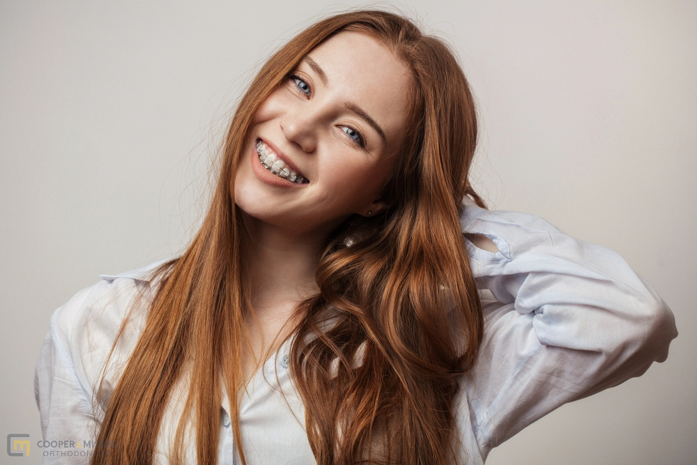 happy young red haired woman in clear braces smiling - Clear Braces vs Metal Braces in Tulsa, OK