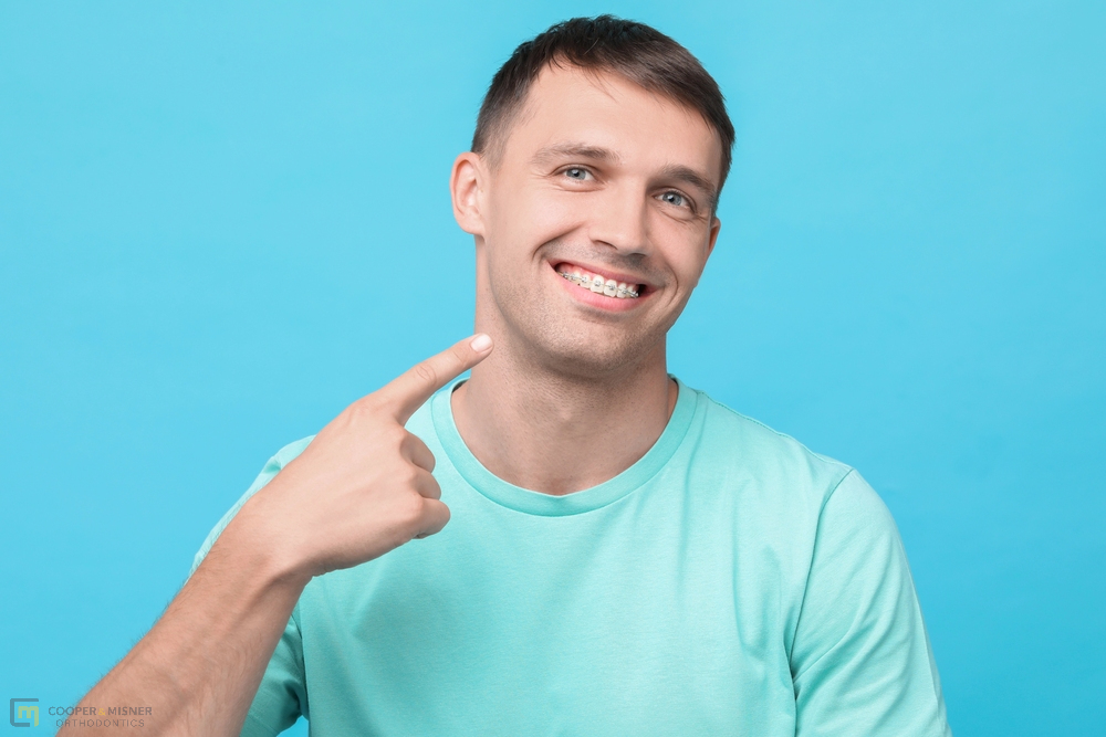 smiling man pointing his metal braces - How to Clean Braces in Tulsa, OK 