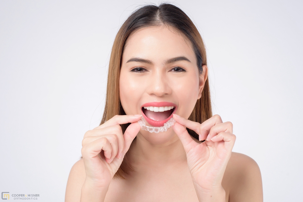 young smiling woman holding invisalign clear aligners studio dental - How Long Does Invisalign Take in Tulsa, OK 